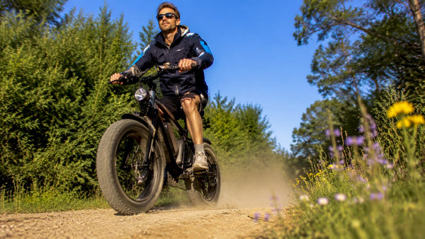 Een man fietst op een stoere fatbike e-bike over een zanderig pad.