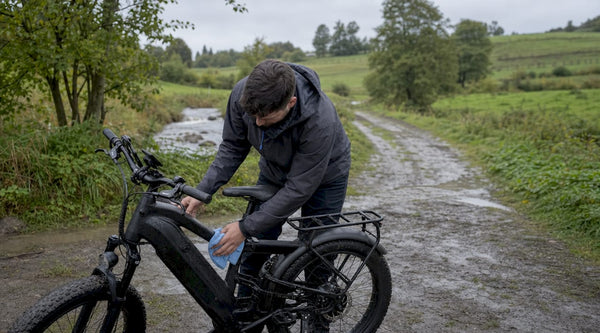 Na een flinke regenbui bekijkt een man aandachtig zijn doorweekte e-bike om te controleren of alles nog goed werkt.