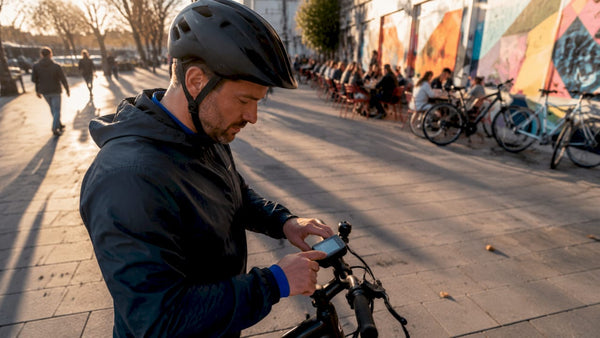 Man bekijkt het display van zijn e-bike terwijl hij door de stad fietst